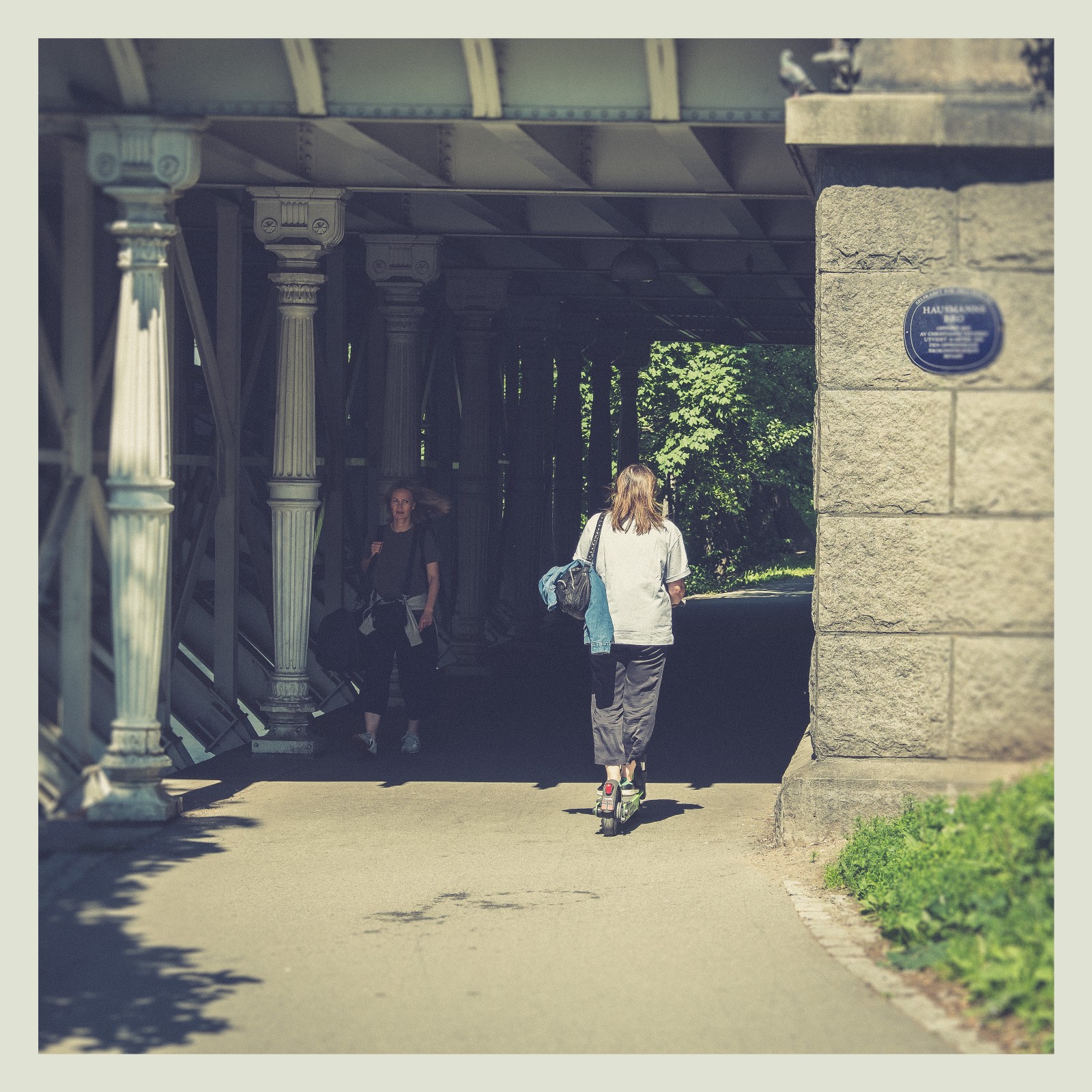 Woman walking under a bridge in Oslo from behind. 