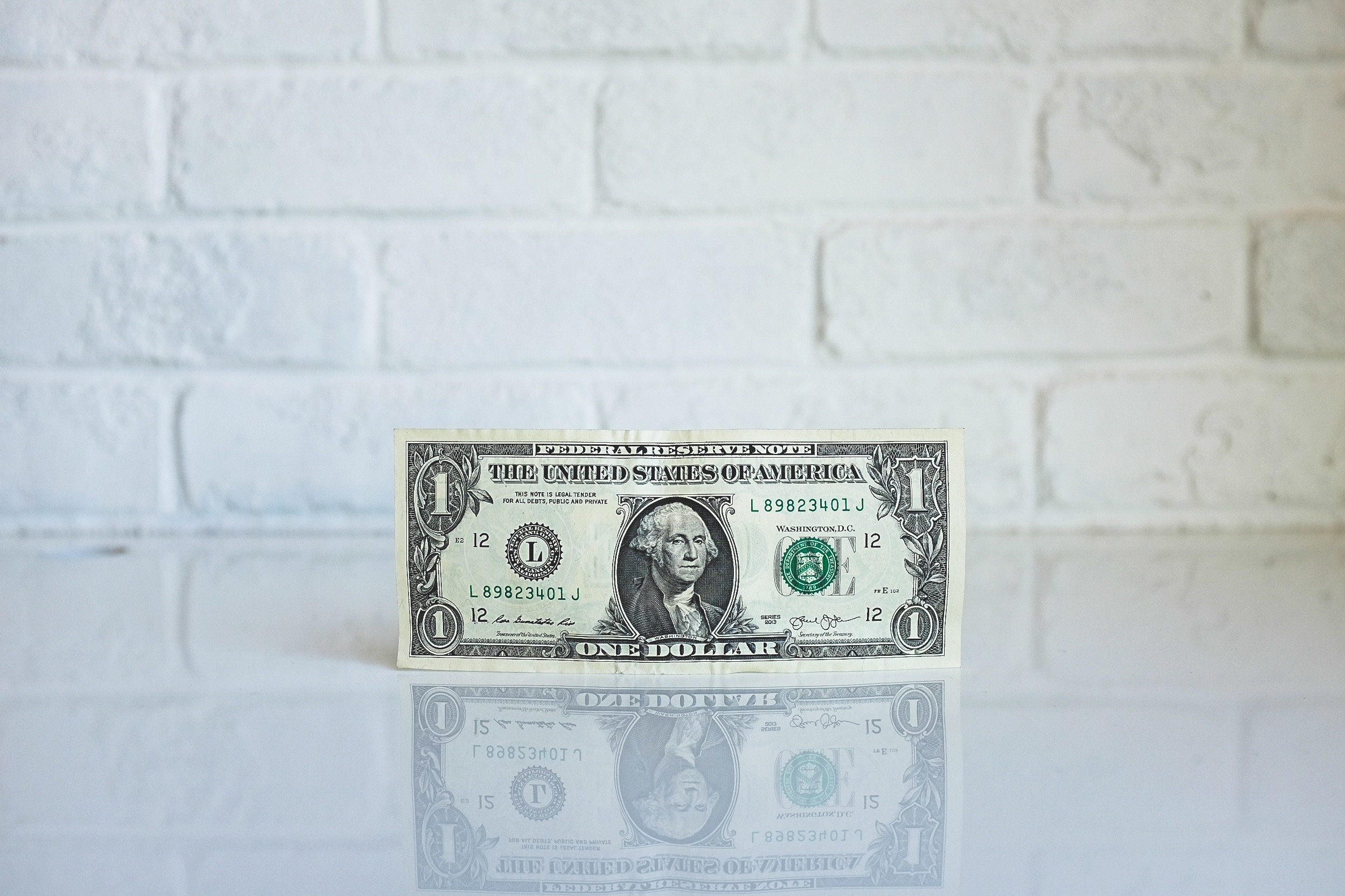 Bilde av en dollarseddel inntil en vegg. Bilde er tatt av NeONBRAND og ligger på nettsiden Unsplash.