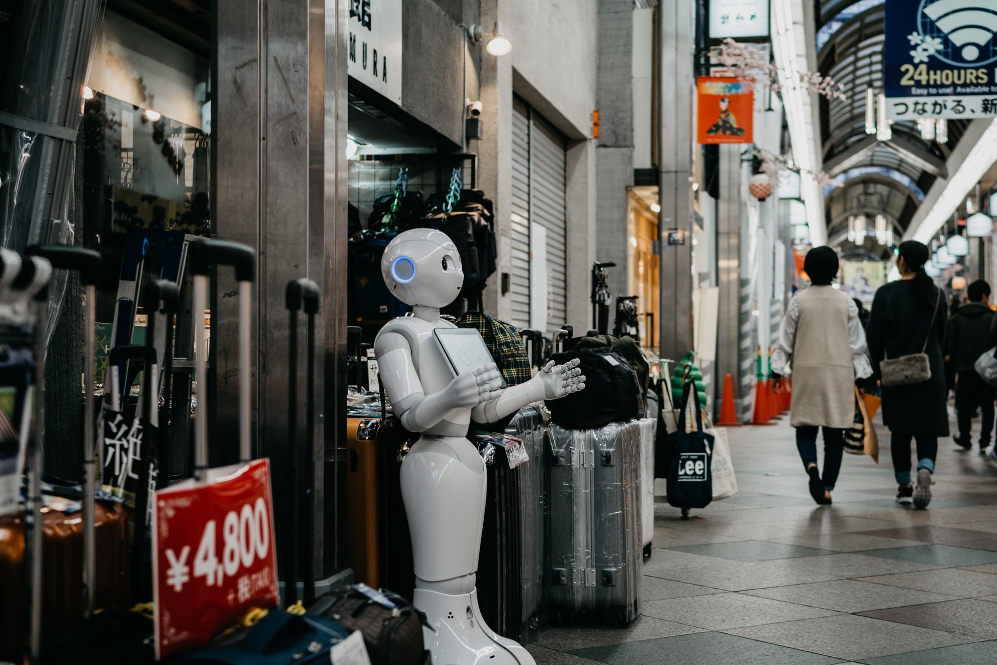 Robot som står utenfor en butikk og tilsynelatende ønsker velkommen