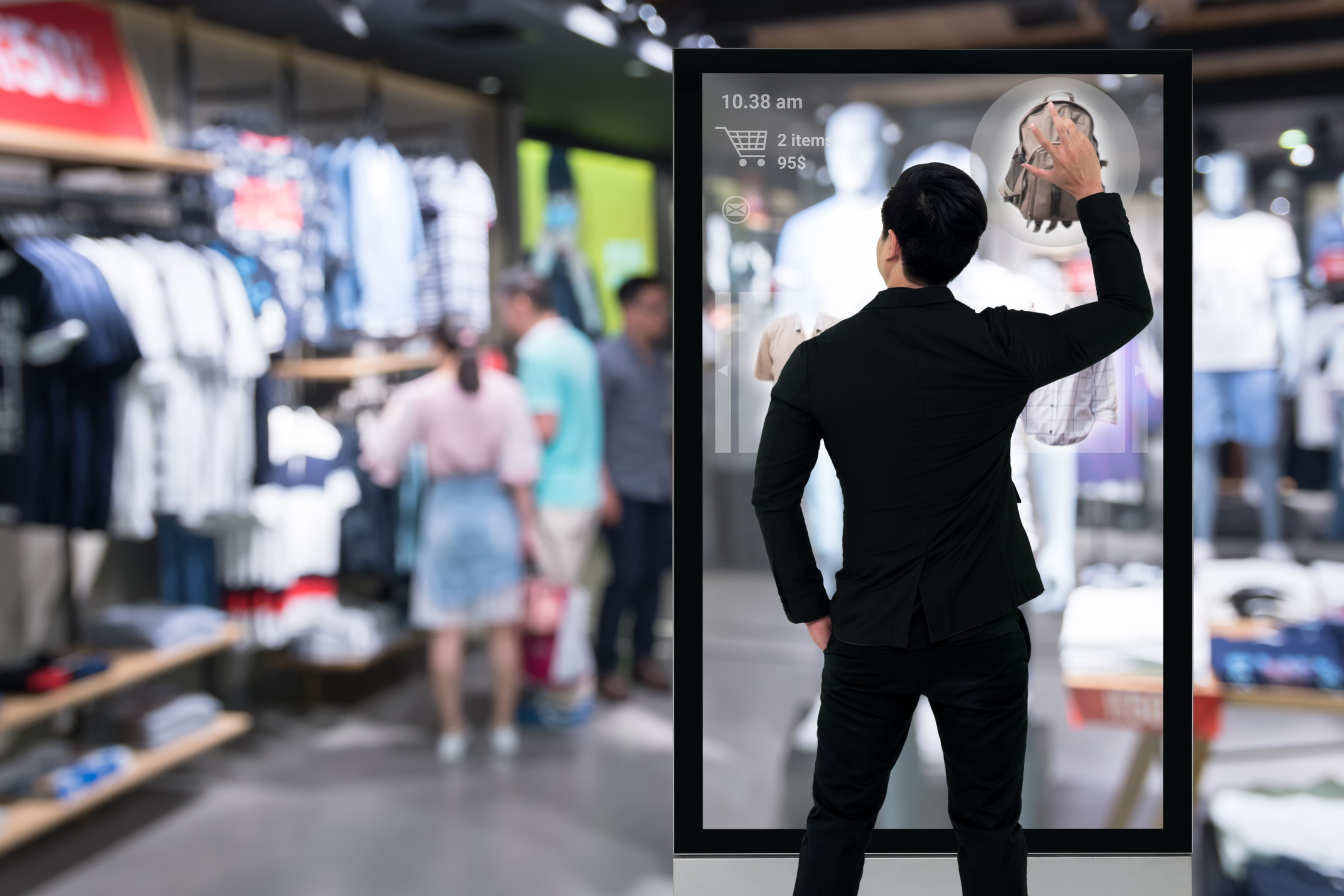 En mann kommuniserer med en stor skjerm inne i en fysisk butikk